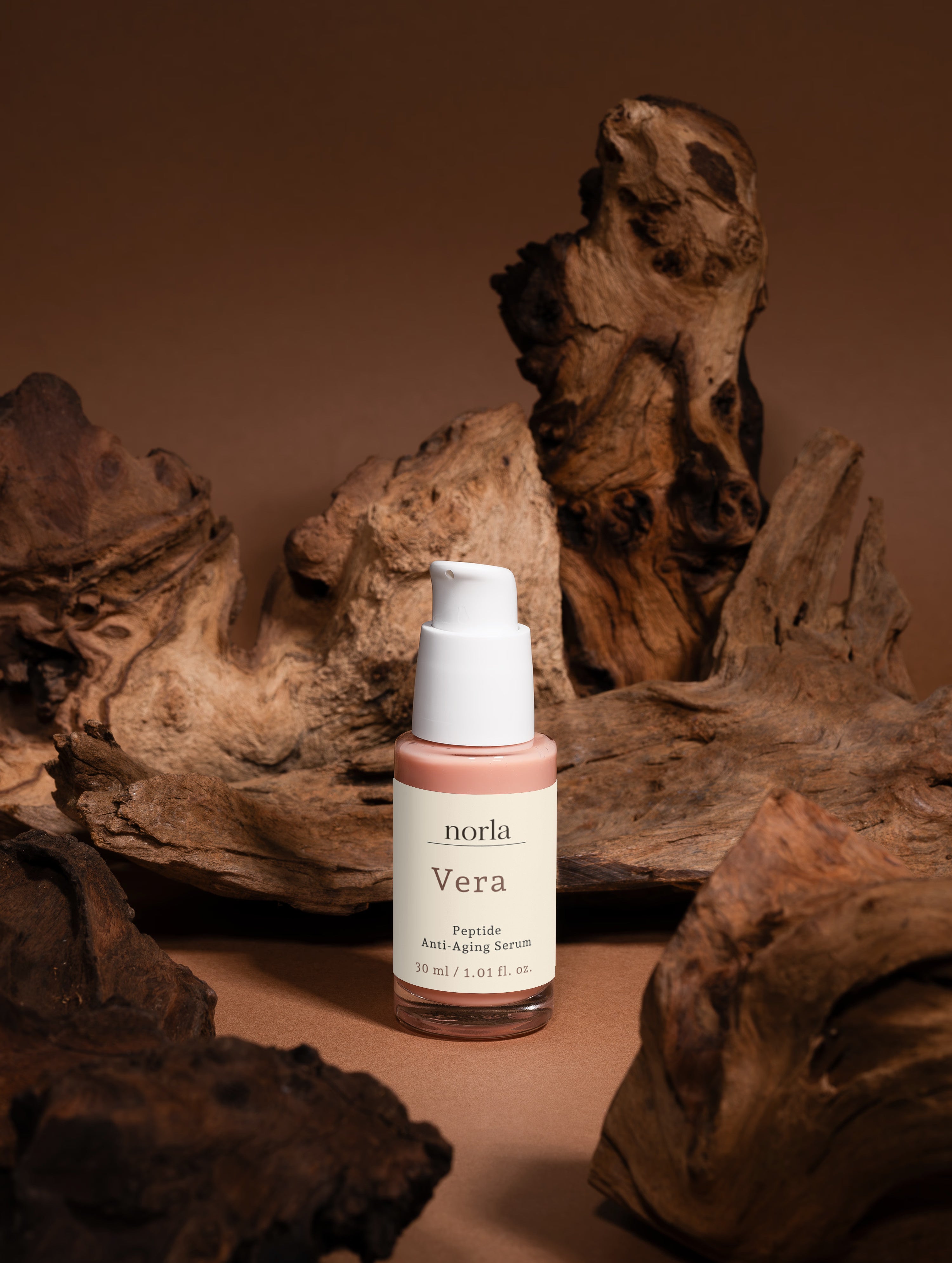 Norla Vera serum shown from the side, highlighting the clear glass bottle and pump dispenser