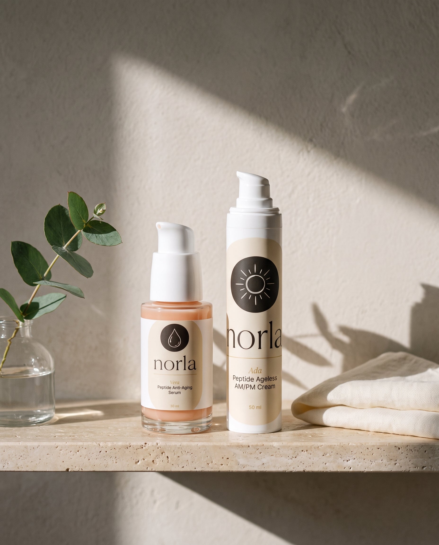 Norla Vera serum and Ada AM/PM cream together on a travertine bathroom shelf