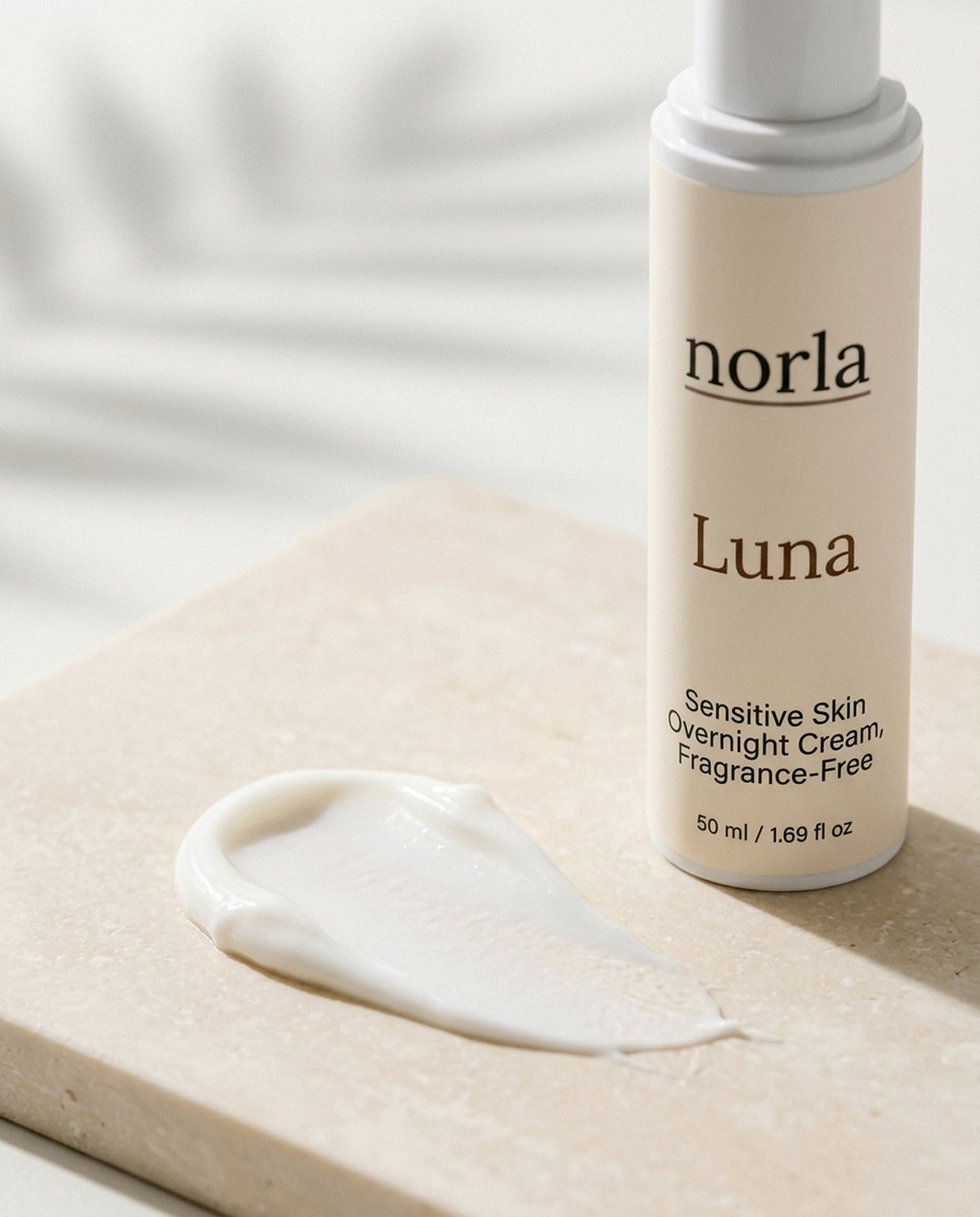 Texture of Luna Sensitive Skin Overnight Cream by Norla: a soft white night cream smear next to the bottle