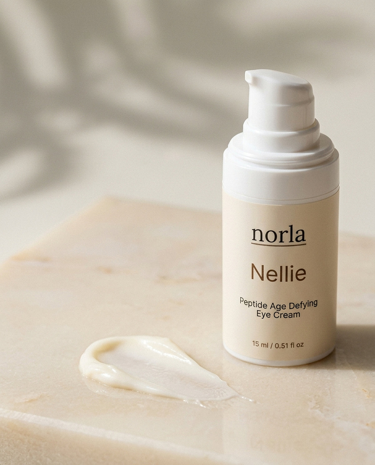 Texture of Nellie Peptide Age-Defying Eye Cream by Norla: a light white eye cream smear next to the bottle