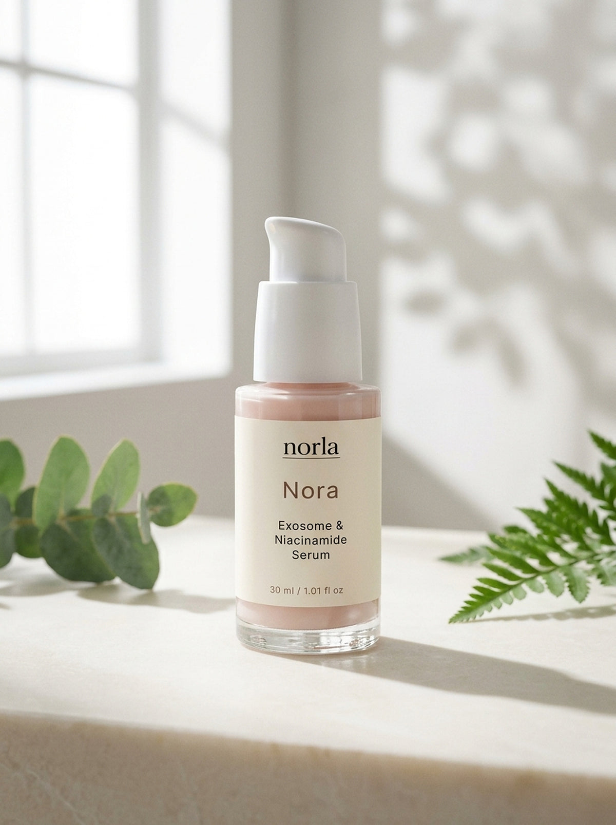 Nora Exosome & Niacinamide Serum 30 ml by Norla, glass pump bottle on a marble surface with eucalyptus and fern