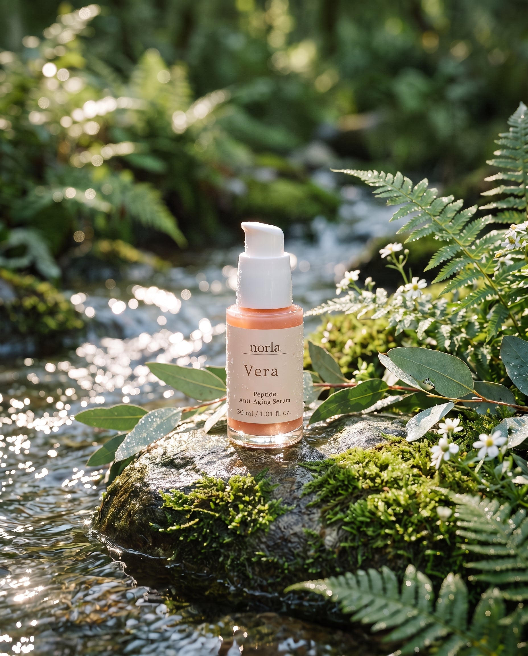 Norla Vera serum bottle standing on a mossy rock beside a woodland stream, surrounded by ferns